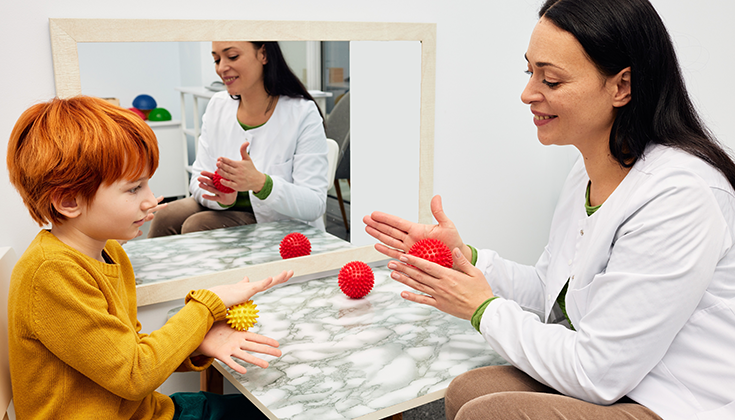 therapist and boy playing with plastic balls