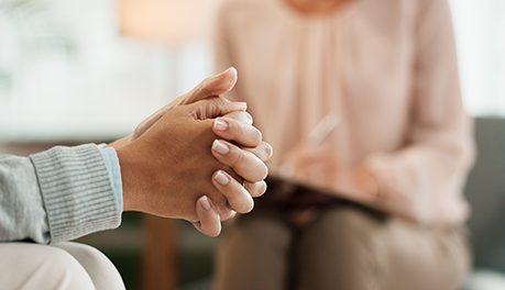 person with hands interlaced nervously with therapist in background
