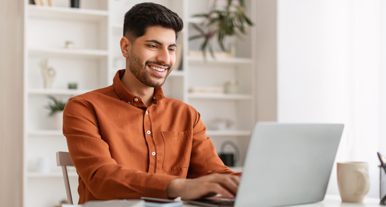 Man smiling while typing on laptop computer