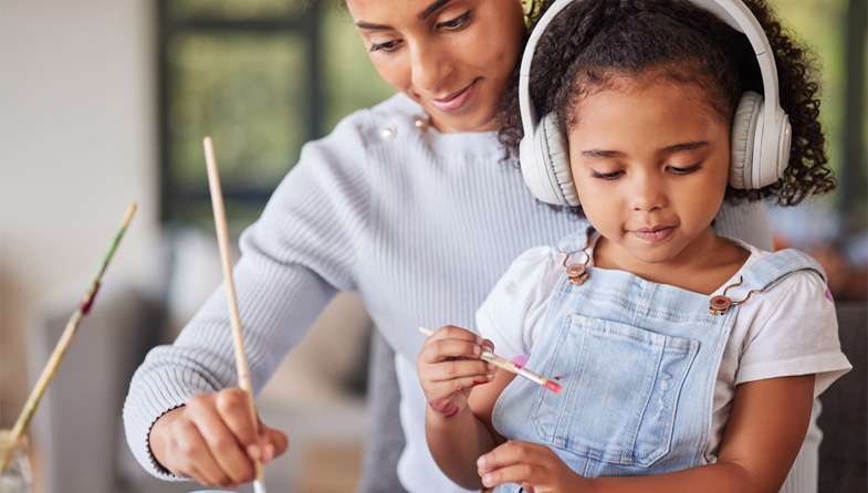 woman painting with child wearing headphones