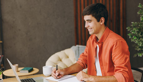 man using computer and taking notes