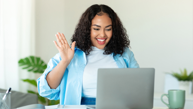 Woman waving to somebody through computer