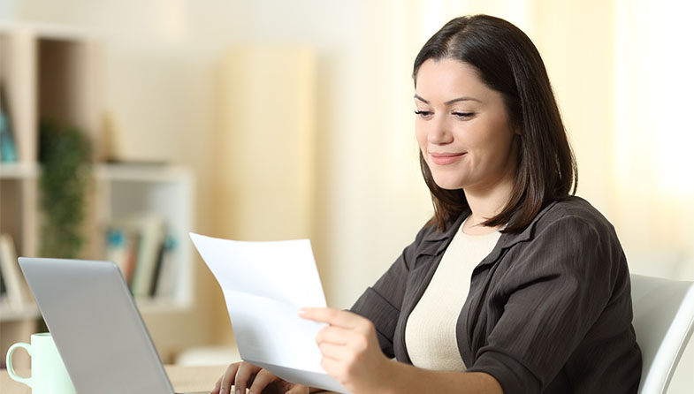 woman at laptop reading paper