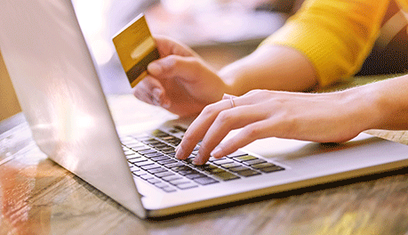 hands typing on laptop and holding credit card