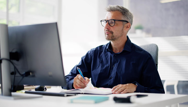man using computer and taking notes